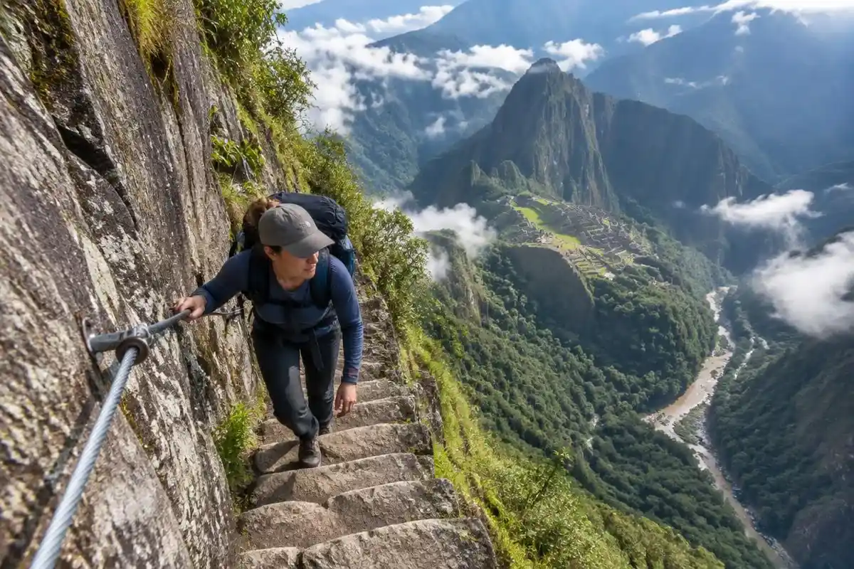Hiker holding the safety cable on the narrow Inca stairs of the Huayna Picchu hike