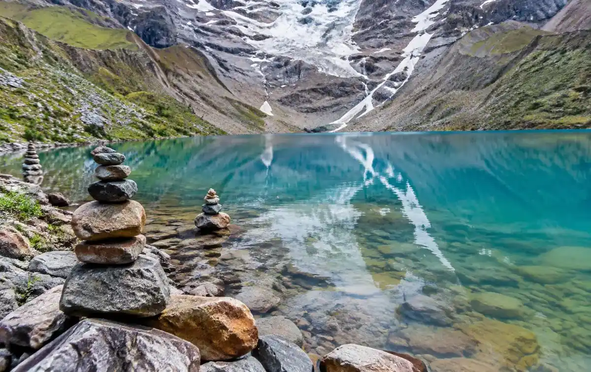Stone cairns on the shore of lake humantay with glacier reflection