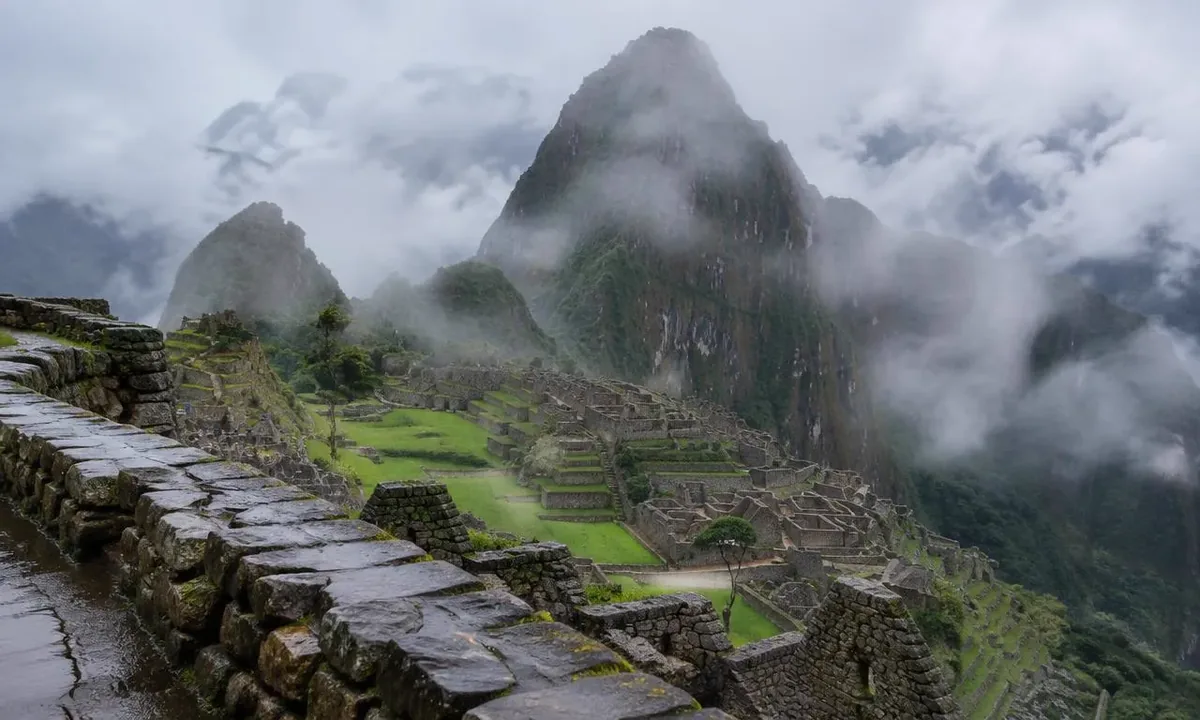 Machu Picchu in January with rainy-season mist drifting over Huayna Picchu and wet green terraces