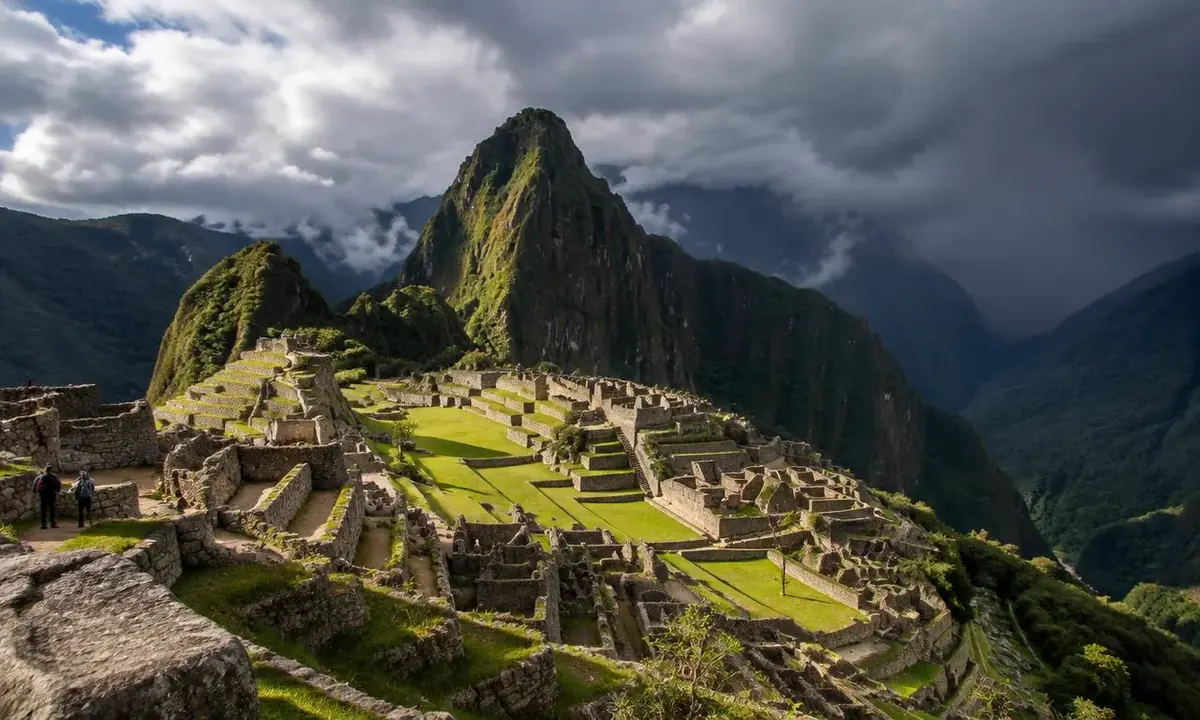 Machu Picchu in October with sunlit ruins and rain clouds building over the peaks