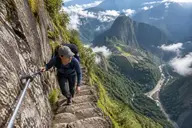 Hiker holding the safety cable on the narrow Inca stairs of the Huayna Picchu hike