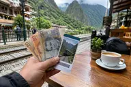 Traveler holding Peruvian soles and a train ticket while budgeting a Machu Picchu trip