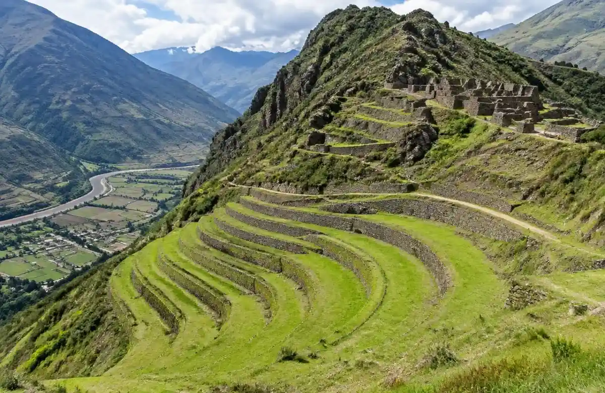 Pisac ruins with curved Inca agricultural terraces sweeping down a Sacred Valley ridge