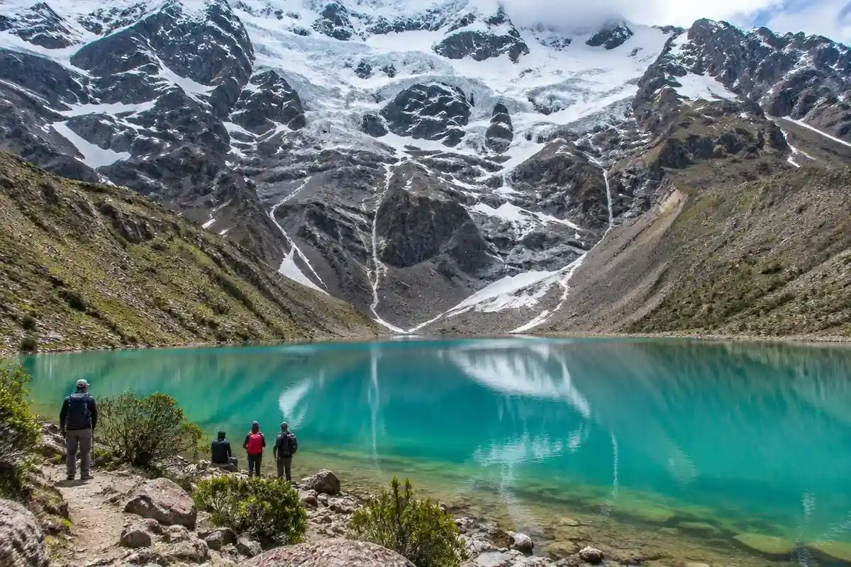 Trekkers at turquoise Humantay Lake under a glacier on day 1 of the Salkantay trek